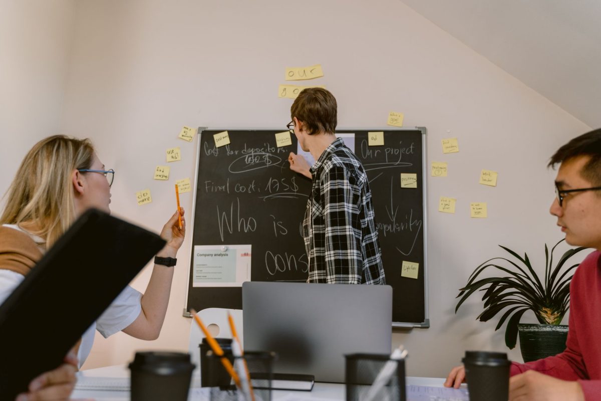 Two coworkers placing colorful sticky notes on a whiteboard during a workshop