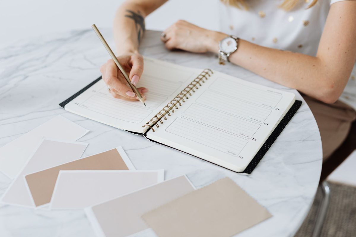Employee writing reflections and goals in a notebook at an organized workspace