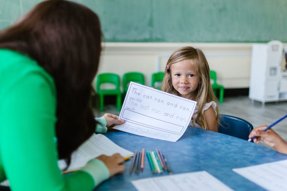 A teacher guiding an elementary school student in a classroom