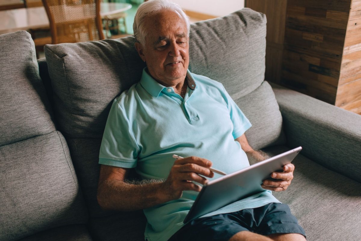 A senior man actively engaged with a digital tablet at home