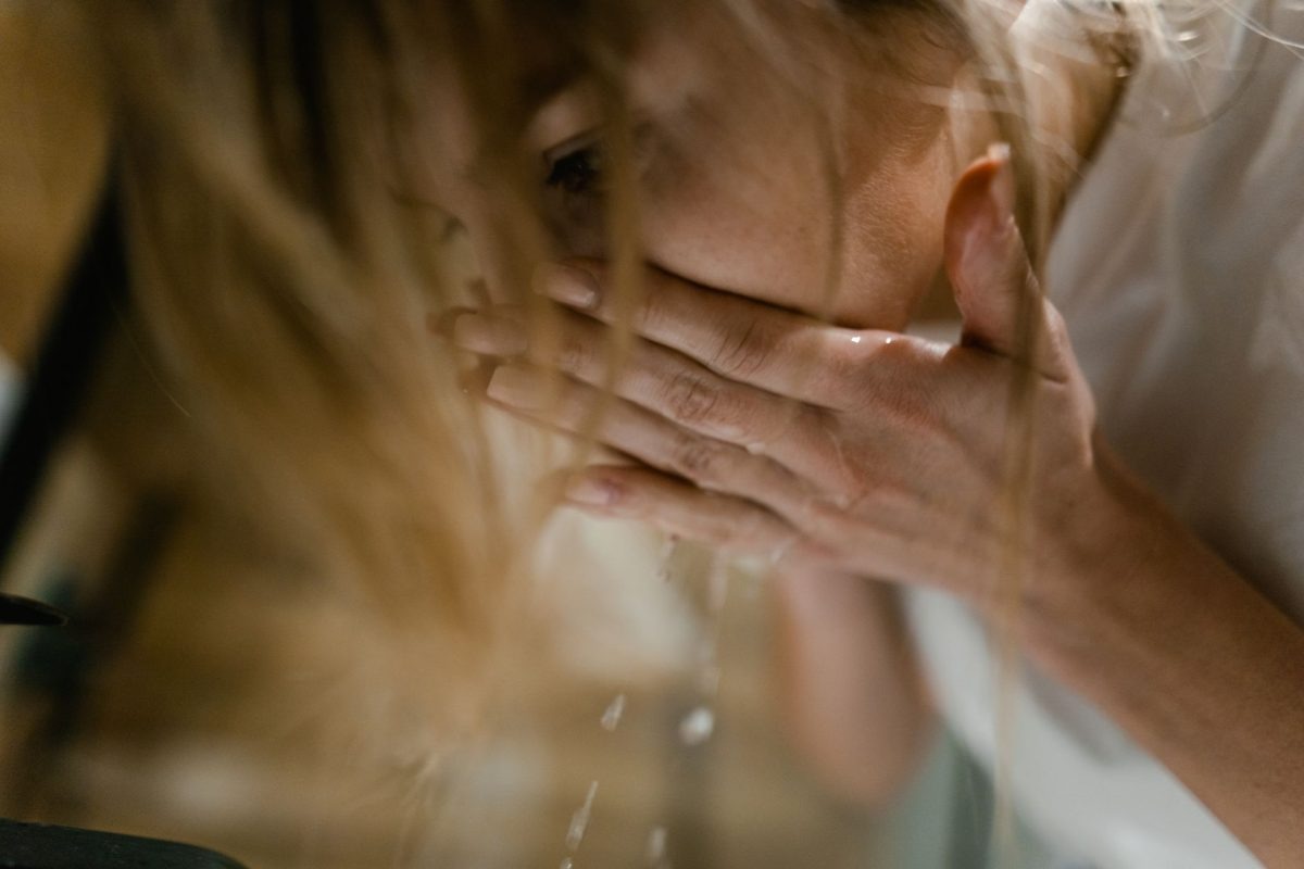 A woman splashing refreshing cold water on her face to reset