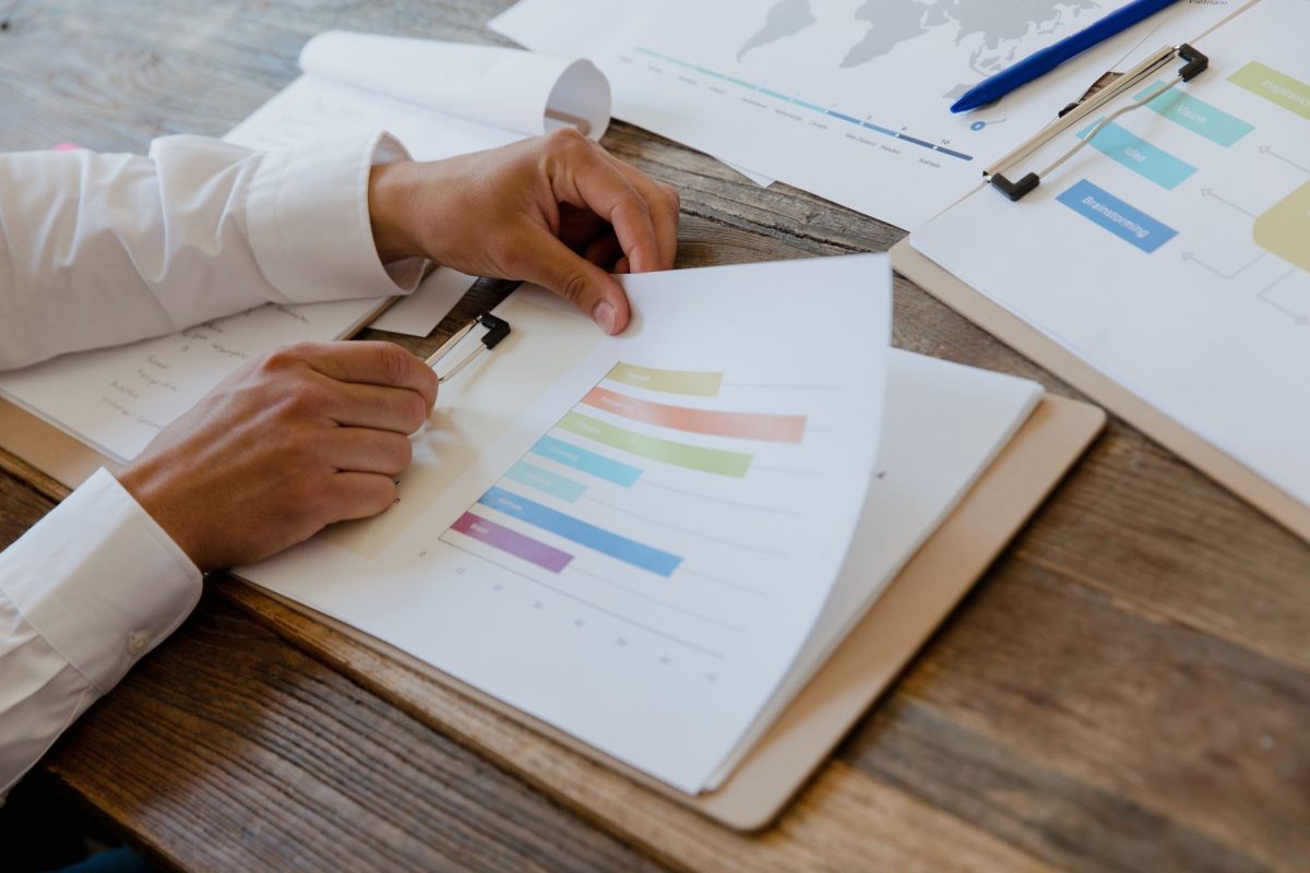 Close-up of an examiner reviewing standardized test score sheets with a normal distribution bell curve