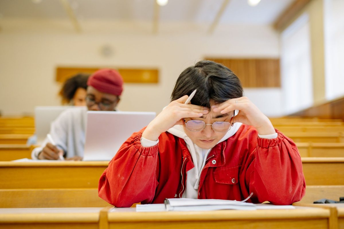 A person sitting at a desk with a laptop, looking thoughtful while navigating a timed digital questionnaire