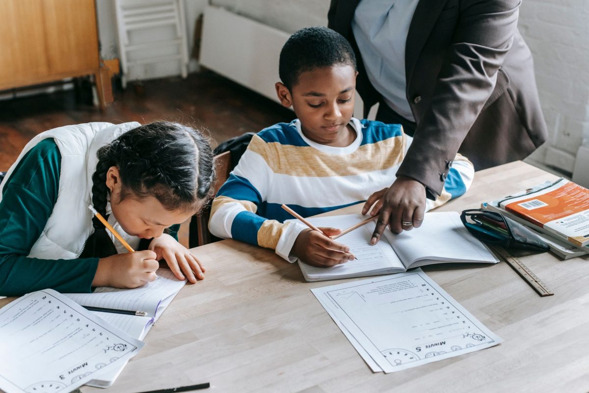 A teacher providing individual academic guidance and learning support to a student at a school desk