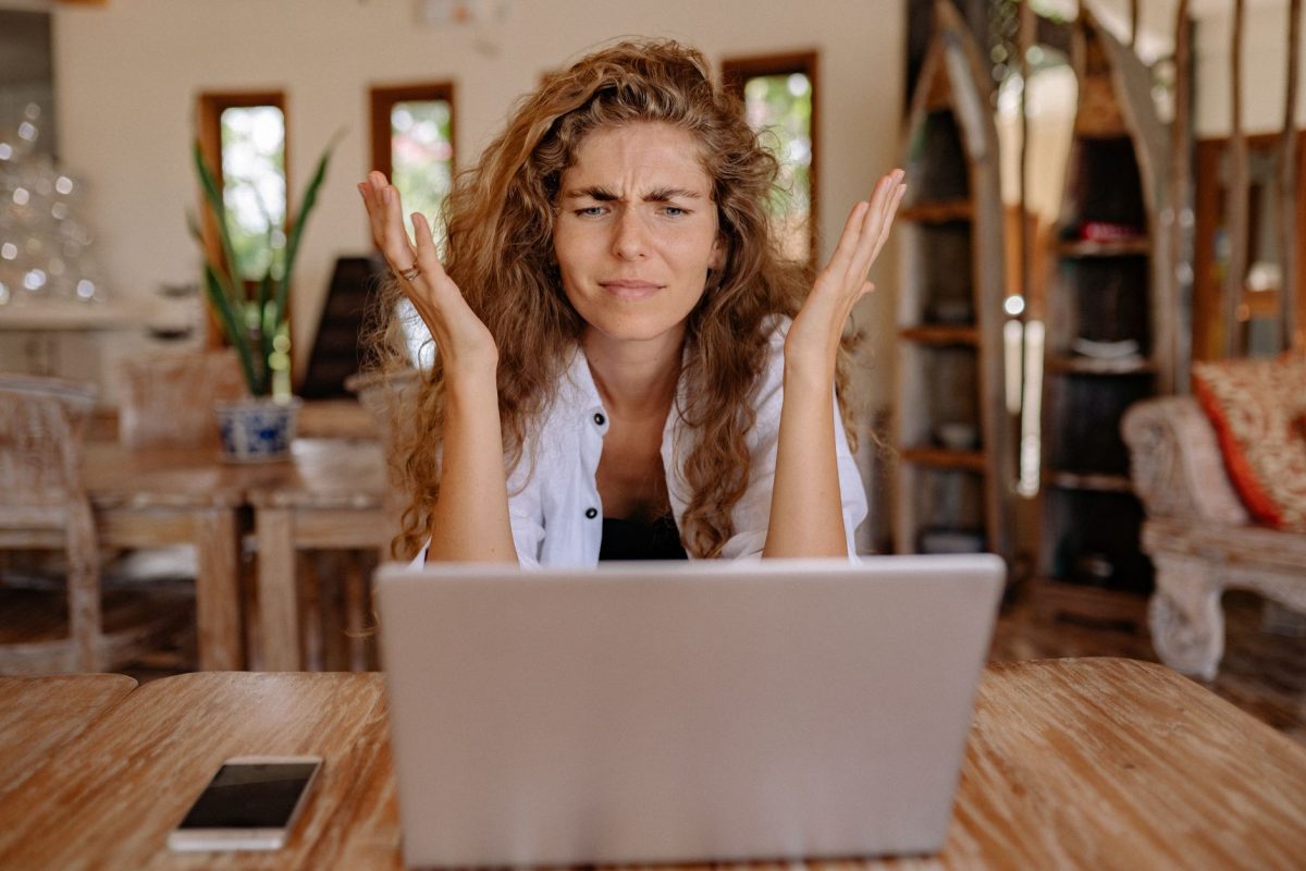 A woman expressing skepticism and frustration while looking at a confusing paywall prompt on her computer