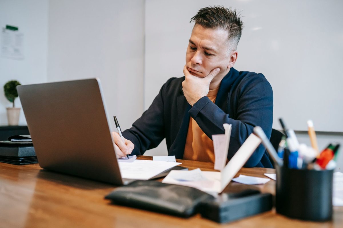 Reflective professional cross-checking research notes and revising assumptions at a desk