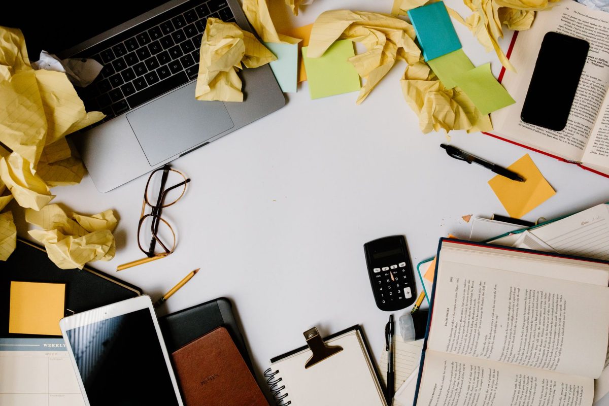 Person working late in solitude at a book-filled desk with notes and sketches