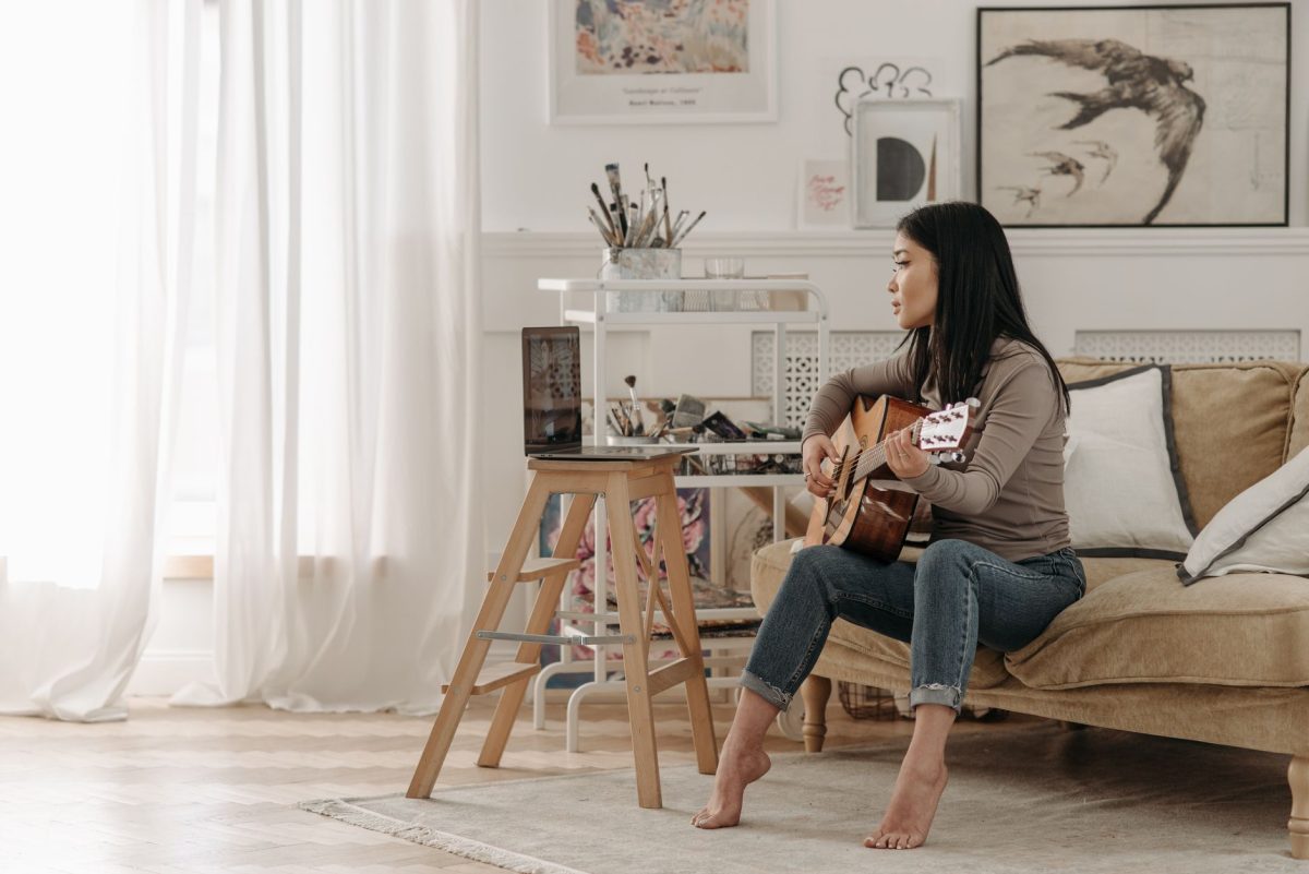 Adult practicing acoustic guitar in a bright living room