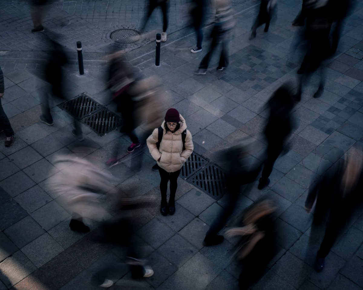 A person experiencing self-conscious worry while sitting in a busy public space